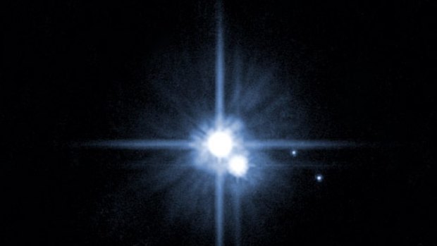 This photo taken by the Hubble Space telescope and released by NASA shows the planet Pluto, centre, with its moons.