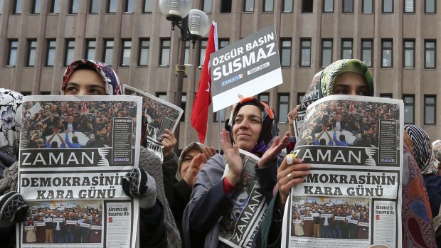 Unbowed: Protesters hold copies of <i>Zaman</i> with a headline that reads "the black day of democracy".