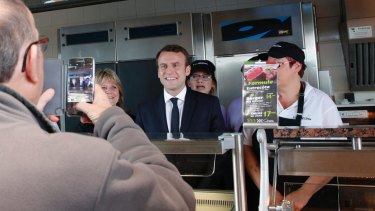 French centrist candidate Emmanuel Macron poses with employees at a fast-food restaurant.