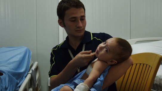 Hisham Haitham comforts his wounded baby cousin Qasid Radhwan at the Athba Field Hospital. Qasid was hit by shrapnel, causing a part of his lung to collapse.
