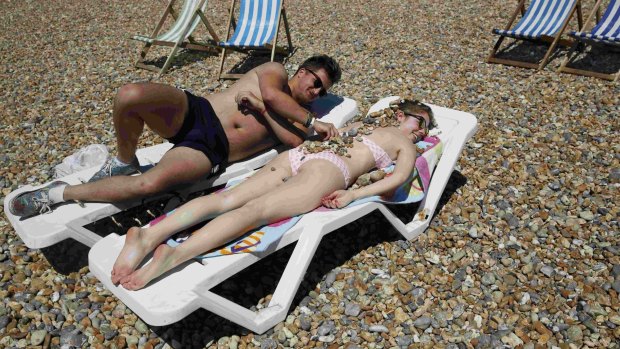 Hadley Eames covers Gemma Cousins with stones as they sunbathe on a hot Summer day at Brighton beach in Britain 