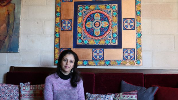 Palestinian artist Maha al-Daya, 39, sits in front of one of her works in her apartment in Gaza. 