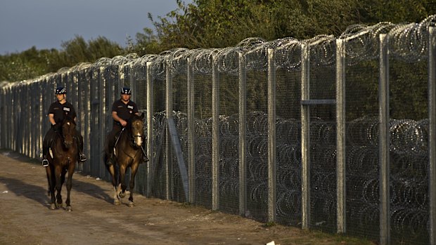 Hungarian police on horses patrol near the fence in Roszke, southern Hungary, after the border between Serbia and Hungary was closed.