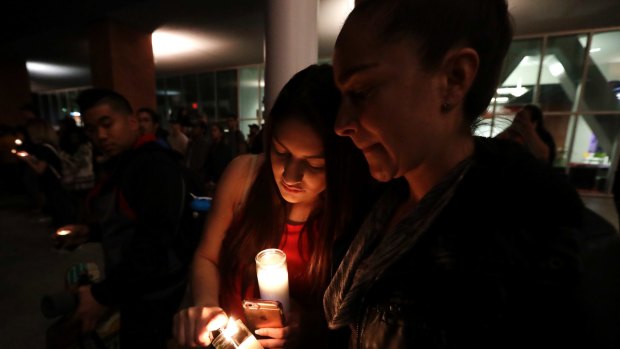 Virginia, right, and Natalie Ramos light candles at a vigil in Las Vegas.
