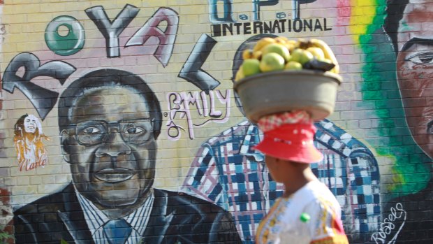 A woman walks past a painting of Zimbabwean President Robert Mugabe in Harare.