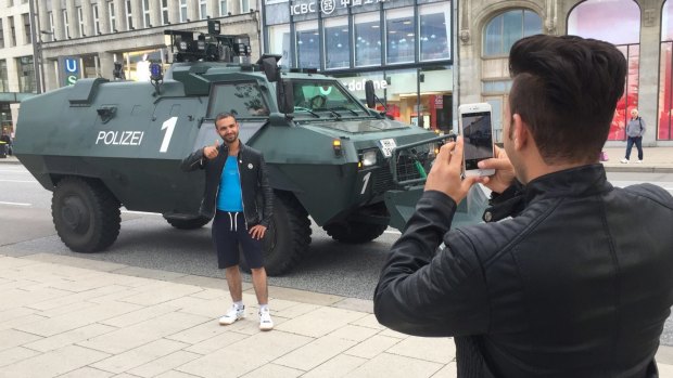 People take photos with police vehicles in Hamburg ahead of G20.
