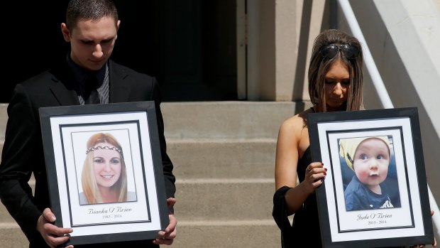 Relatives of Bianka and Jude O'Brien carry their photographs at their funeral.
