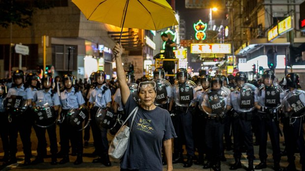 A pro-democracy activist holds a yellow umbrella in front of a police line on a street in Hong Kong's Mong Kok district on November 25 last year. 
