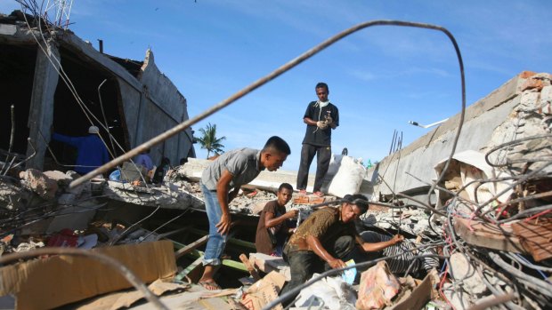 People search for usable items in the rubble of a building that collapsed during Wednesday's earthquake in Trienggadeng, Aceh province, Indonesia.