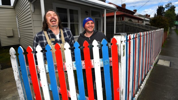 James Best (left), of Seddon, painted his front fence in Bulldogs colours after losing a bet with his neighbour Paul Leworthy.