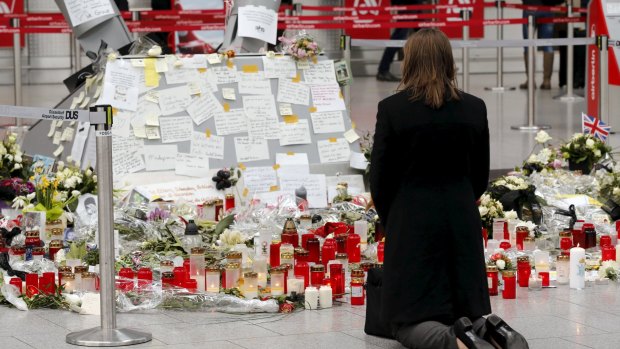A woman kneels in front of candles and flowers as she prays for the victims of Germanwings Flight 4U9525 at Dusseldorf airport on April 1.