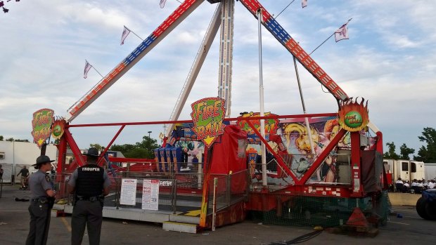 Authorities stand near the Fire Ball amusement ride after the ride malfunctioned injuring several at the Ohio State Fair.