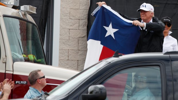 US President Donald Trump, accompanied by first lady Melania Trump, holds up a Texas flag after speaking with supporters outside Firehouse 5 in Corpus Christi, Texas.