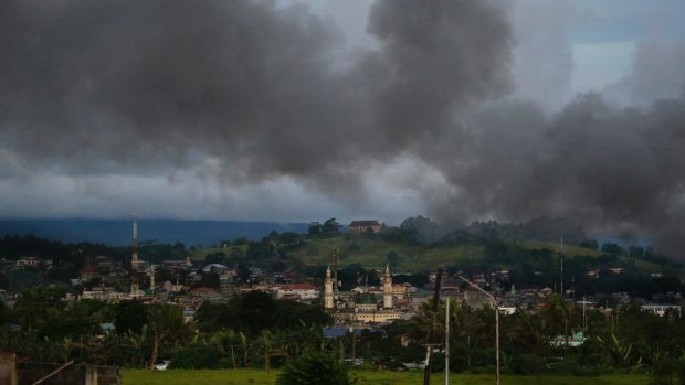 Black smoke from continuing military air strikes rises above a mosque in Marawi.