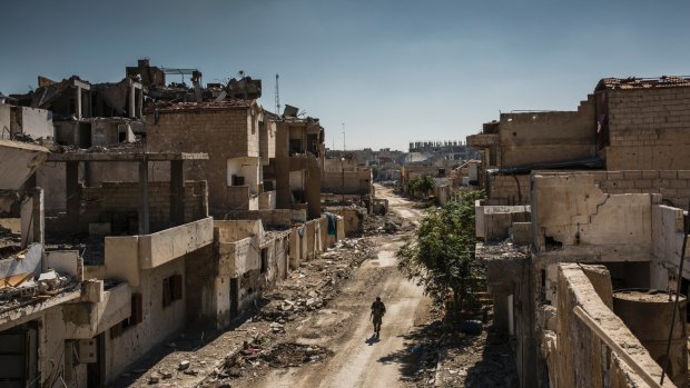 A Syrian Democratic Forces fighter walks through the destroyed streets of Raqqa after the expulsion of most if not all IS fighters.