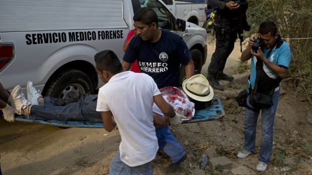 Forensic workers remove the body of a man shot four times in an empty lot between residences in the Leyes de Reforma neighbourhood of Acapulco, Mexico, earlier this month.