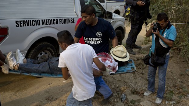 Forensic workers remove the body of a man shot four times in an empty lot between residences in the Leyes de Reforma neighbourhood of Acapulco, Mexico, earlier this month.