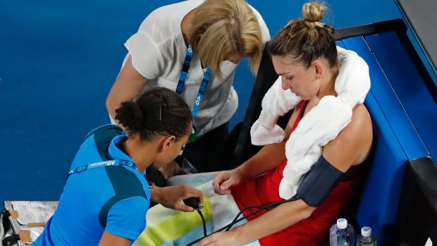 The heat and a long tournament take their toll on Simona Halep as she receives treatment from medical staff.