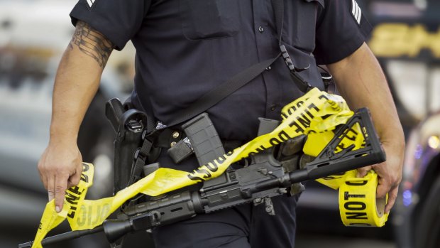 A police officer deploys tape in San Bernardino, California.