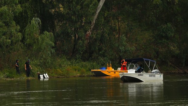 Police divers enter the water in the search for a missing man at the Murrumbidgee River. 