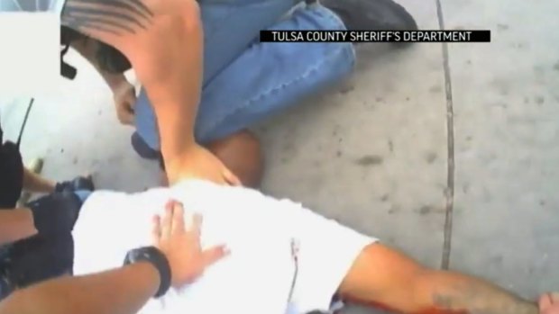Police restrain Eric Harris, 44, after he was chased down by a Tulsa County deputy, and then shot by a reserve deputy in this screen grab from a police video. 
