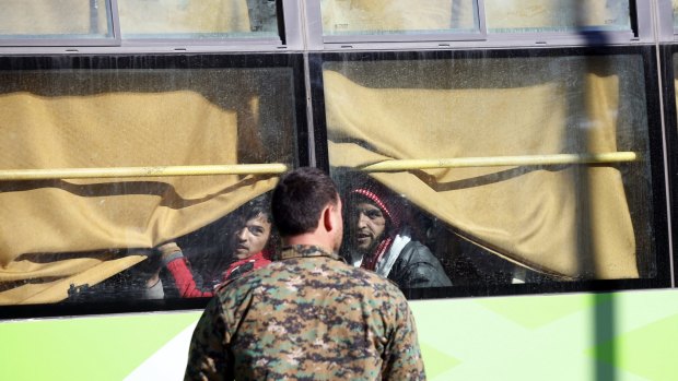 Gunmen on a bus leave the Waer neighborhood in the central city of Homs on Wednesday.  local deal with government forces that allows them safe passage to areas in the country's north.