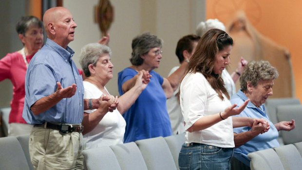 Contradictions: Parishioners pray for the Virginia victims.
