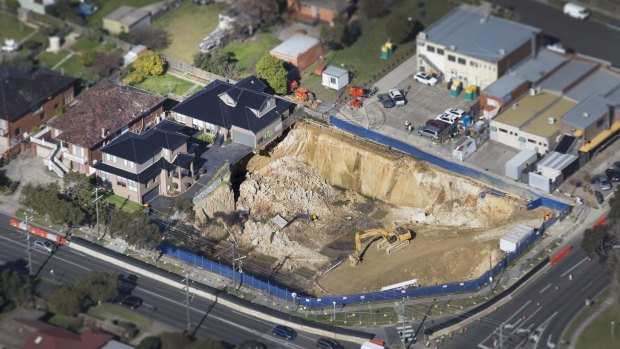 An aerial shot shows how close two townhouses came to falling into the collapsed pit.