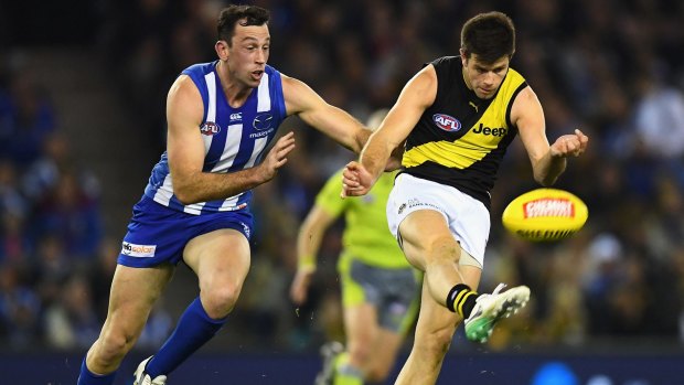 Richmond skipper Trent Cotchin gets his kick away as Roo ruckman Todd Goldstein gives chase.