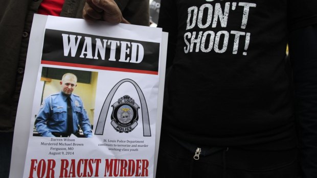 Protesters hold a "Wanted" poster of the police officer who shot Michael Brown.