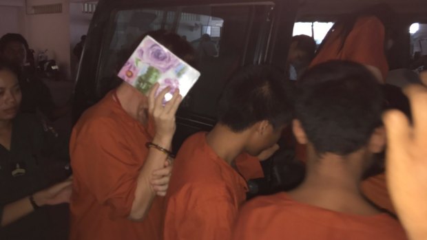 Tammy Davis-Charles hides her face as she is led back to her jail cell from Phnom Penh court on Thursday.