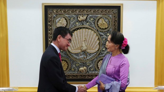 Myanmar's State Counselor and Foreign Minister Aung San Suu Kyi, right, shakes hands with Japanese Foreign Minister Taro Kono.