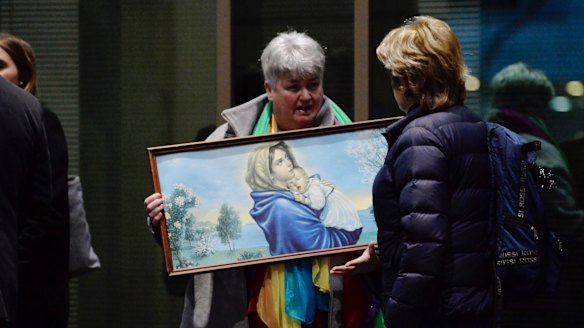 Julie Cameron holds a painting of the Virgin Mary and child outside the Melbourne Magistrates Cout.