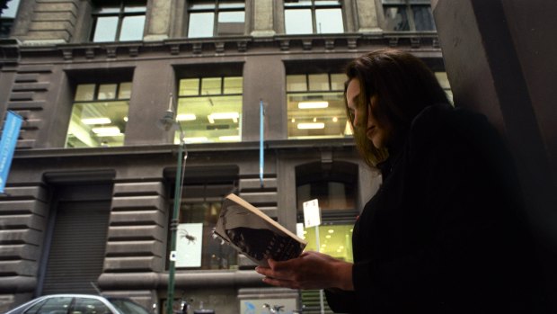 A woman reads a book in front of the Flinders Lane building in 2002, before it became a library. 