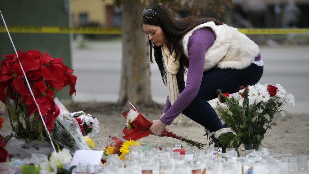 Jennifer Caballero places flowers at a makeshift memorial to the victims of Wednesday's shooting rampage in San Bernardino.