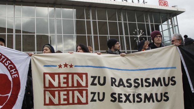 People protest in front of Cologne's main railway station. The sign reads: "No to Racism, No to Sexism". 