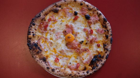 Pizza topped with mozzarella, pancetta, black pepper, chilli oil and an egg yolk.
