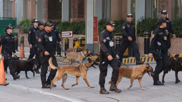 Bomb sniffing dogs walk outside a hotel at the Resorts World Manila complex.