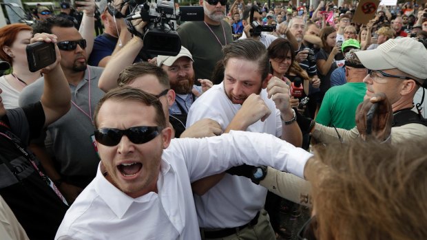 Two supporters of white nationalist Richard Spencer clash with a crowd of protesters after Spencer spoke at the University of Florida.