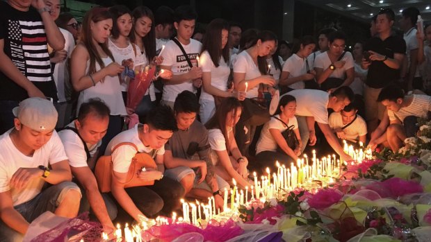 Mourners light candles and lay flowers in front of a memorial outside the casino.