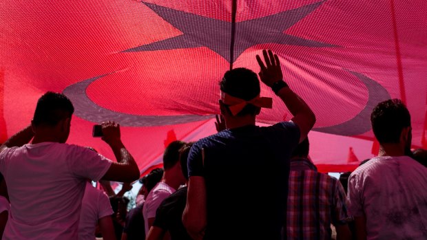 People stand under a huge Turkish flag during a march around Kizilay Square in  Ankara on Saturday.