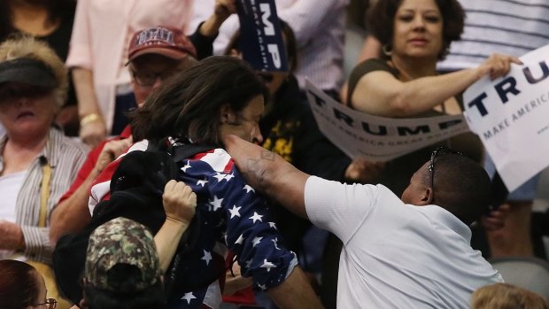 Trump protester Bryan Sanders, center left, is punched by a Trump supporter as he is escorted out of Donald Trump's rally.