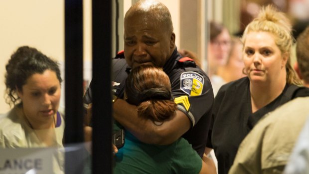 A Dallas Area Rapid Transit police officer is comforted at the Baylor University Hospital.