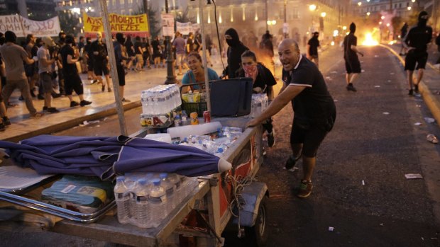 Food vendors rush to clear the area in Syntagma Square during police clashes with protesters in Athens on Wednesday.