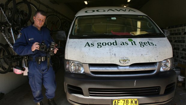 A police officer  finger printing and photographing Mr Chin's van.
