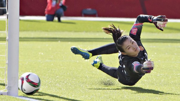 The turf can hurt: China's goalkeeper Wang Fei dives in an attempt to stop a penalty. 