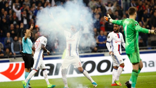 Lyon's Corentin Tolisso is masked by smoke as he celebrates scoring.