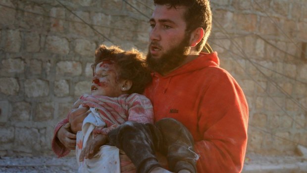 Pulled from the wreckage: A man carries a Syrian child to safety following airstrikes on residential areas of Aleppo, Syria in November. 