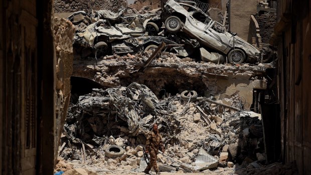 An Iraqi Special Forces soldier walks in front of a wall of debris on a road in West Mosul, Iraq.