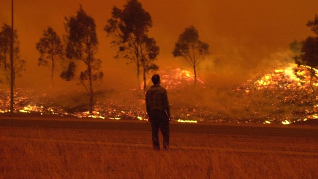 A residents watches grassland burn in Gordon during the devastating 2003 Canberra bushfires.